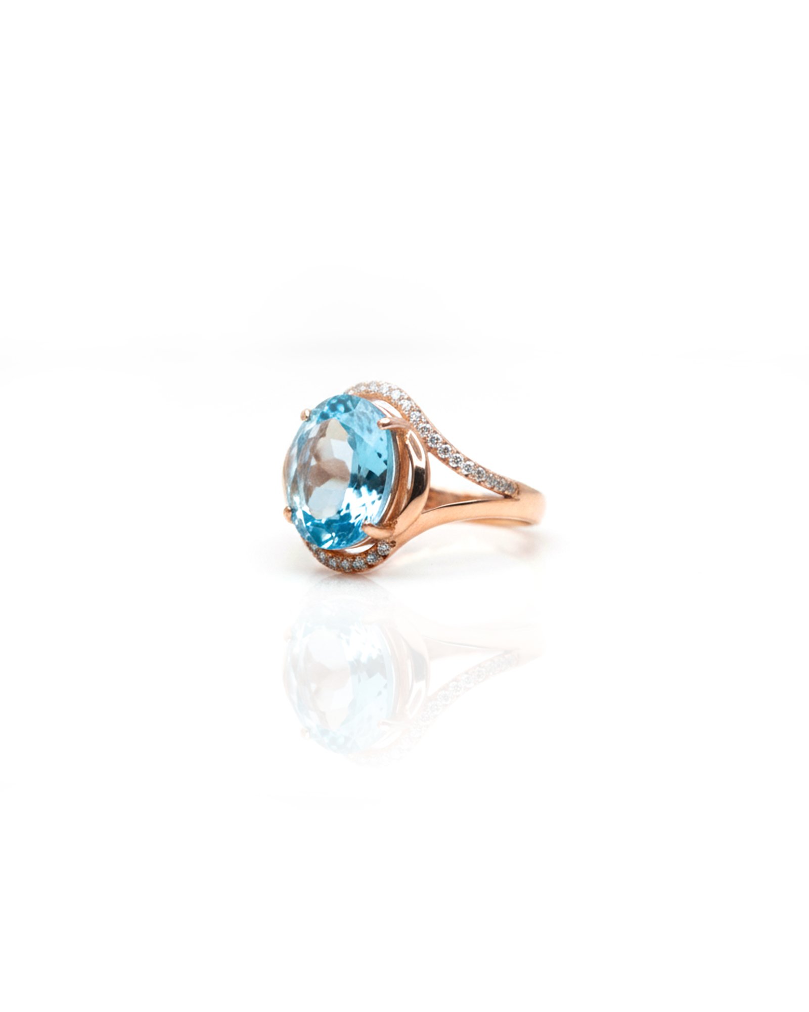 Side view of rose gold plated 925 silver oval blue topaz halo ring showing split shank and accent stones – L66648