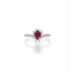 Front view of 925 silver ruby and white sapphire halo cluster ring with oval ruby center and daisy-style floral design